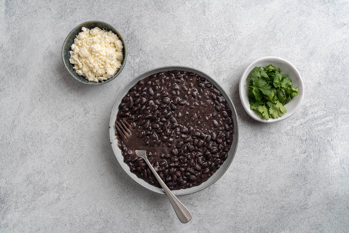 Taste of Home Instant Pot Black Beans recipe photo of serving the beans with queso fresco and cilantro.
