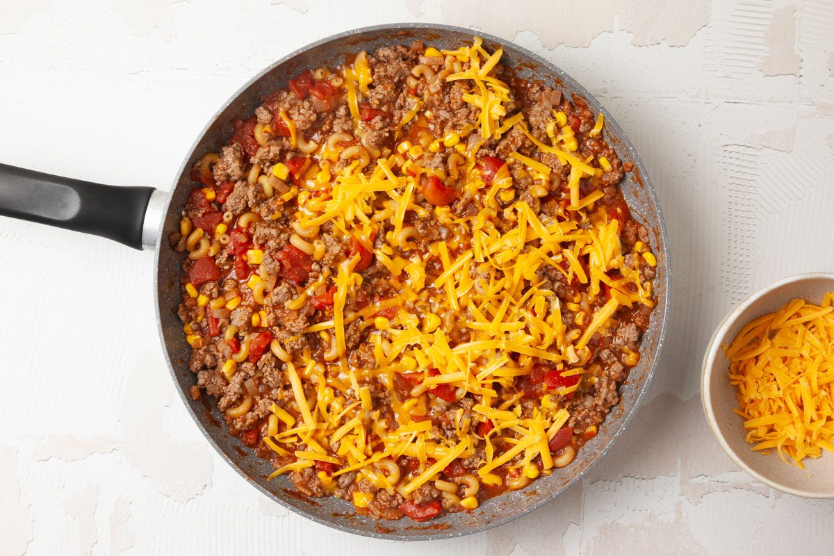 Step 3 of Taste of Home Mexi-Mac Skillet is to top with cheddar cheese and stir in