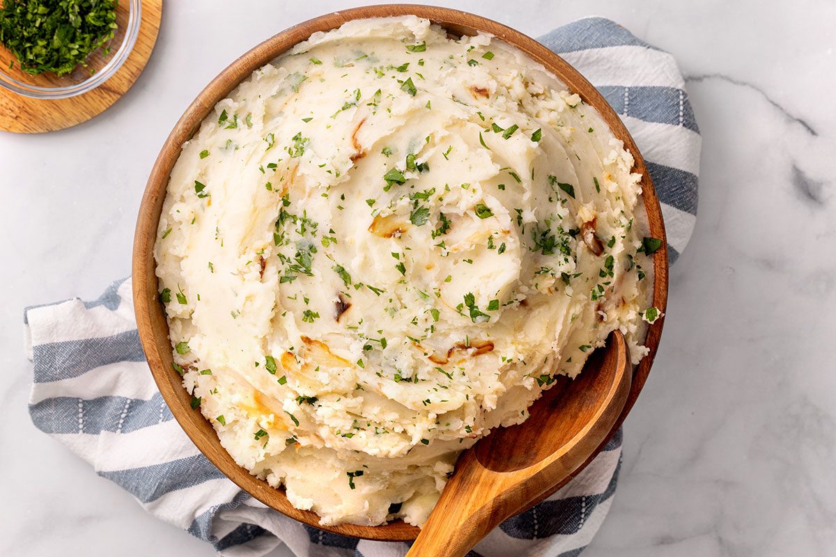 Overhead view of Onion Mashed Potatoes in a wooden serving bowl topped with chopped parsley for Taste of Home