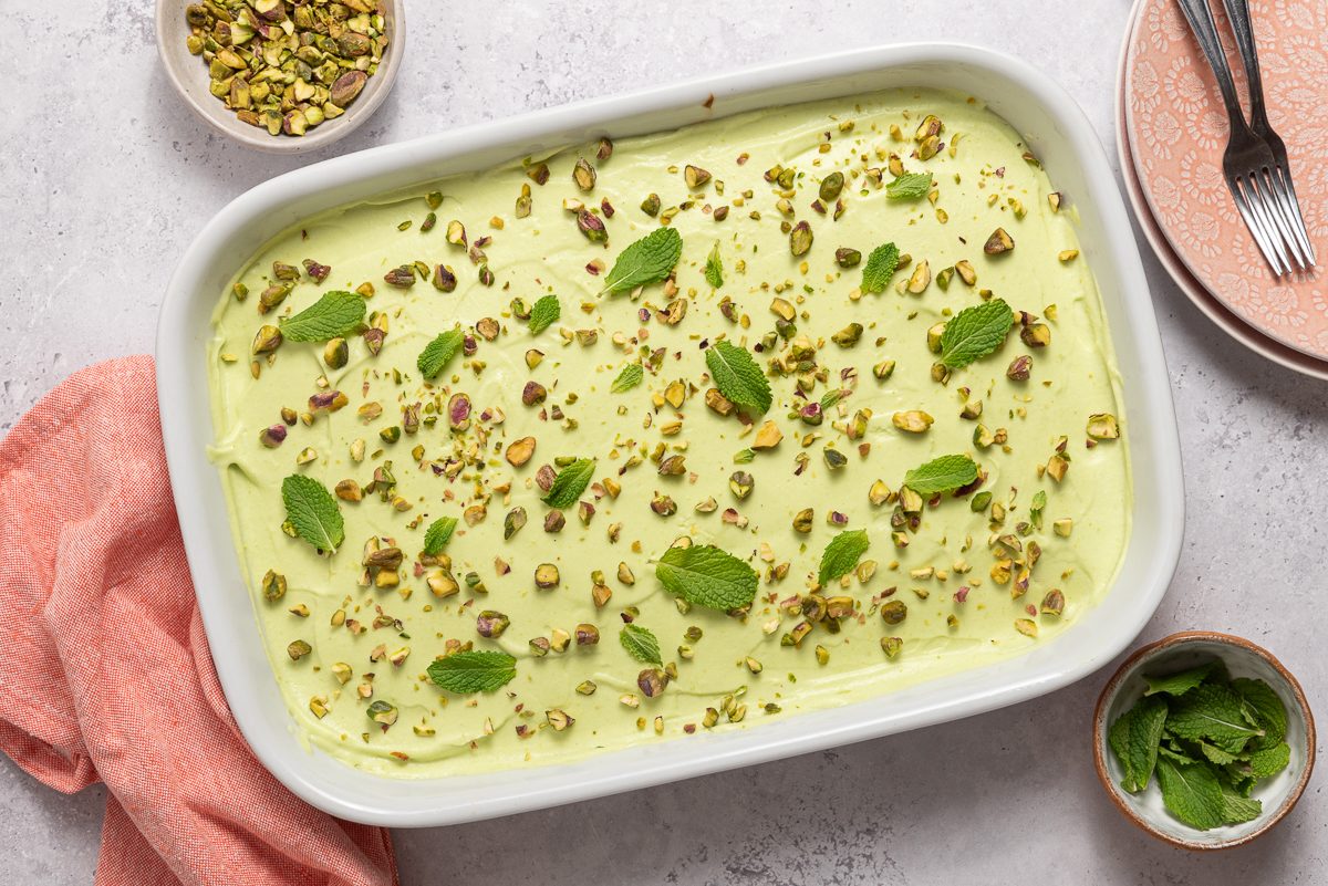 Frosted Pistachio Cake Sprinled With Pistachios And Mint Leaves