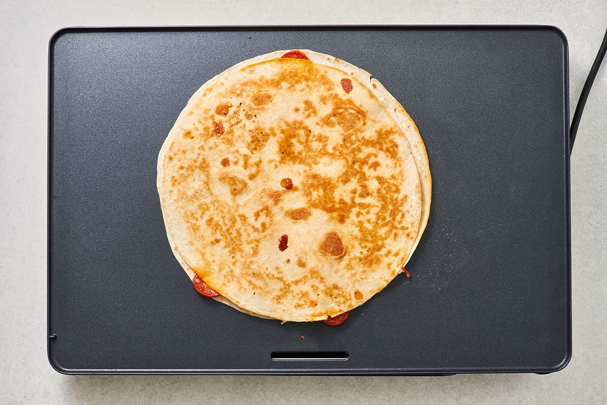 Cooked pizza quesadilla on a griddle