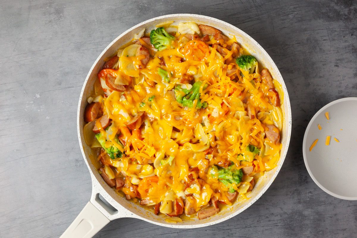 Step 2 of Taste of Home Scalloped Potatoes and Sausage is to add the vegeteables and let them cook before melting the cheese on top