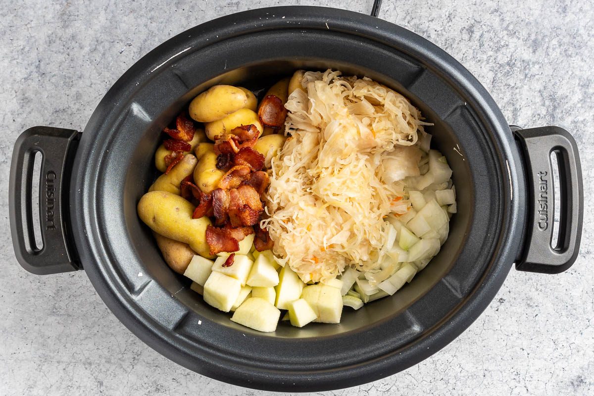 Taste of Home Slow Cooker Pork and Sauerkraut photo of the sauerkraut, potatoes, onion, apple and bacon in the slow cooker.