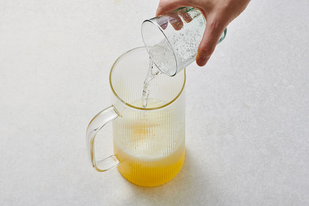 Pouring club soda into the lemonade in a pitcher