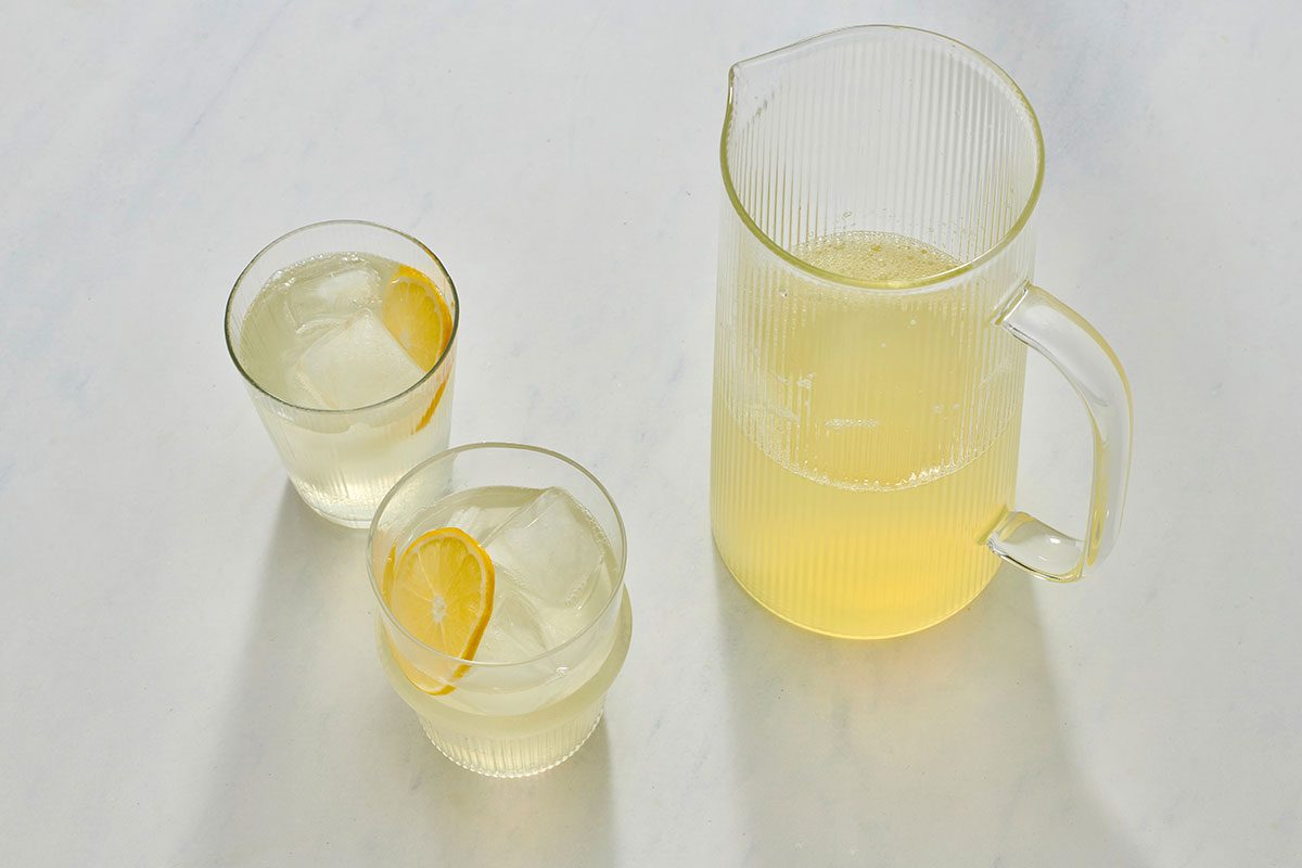 Lemonade in glasses filled with ice, with a pitcher nearby