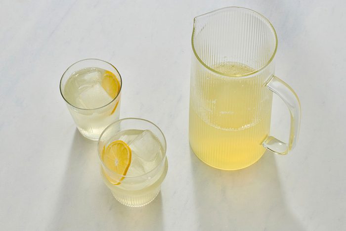 Lemonade in glasses filled with ice, with a pitcher nearby