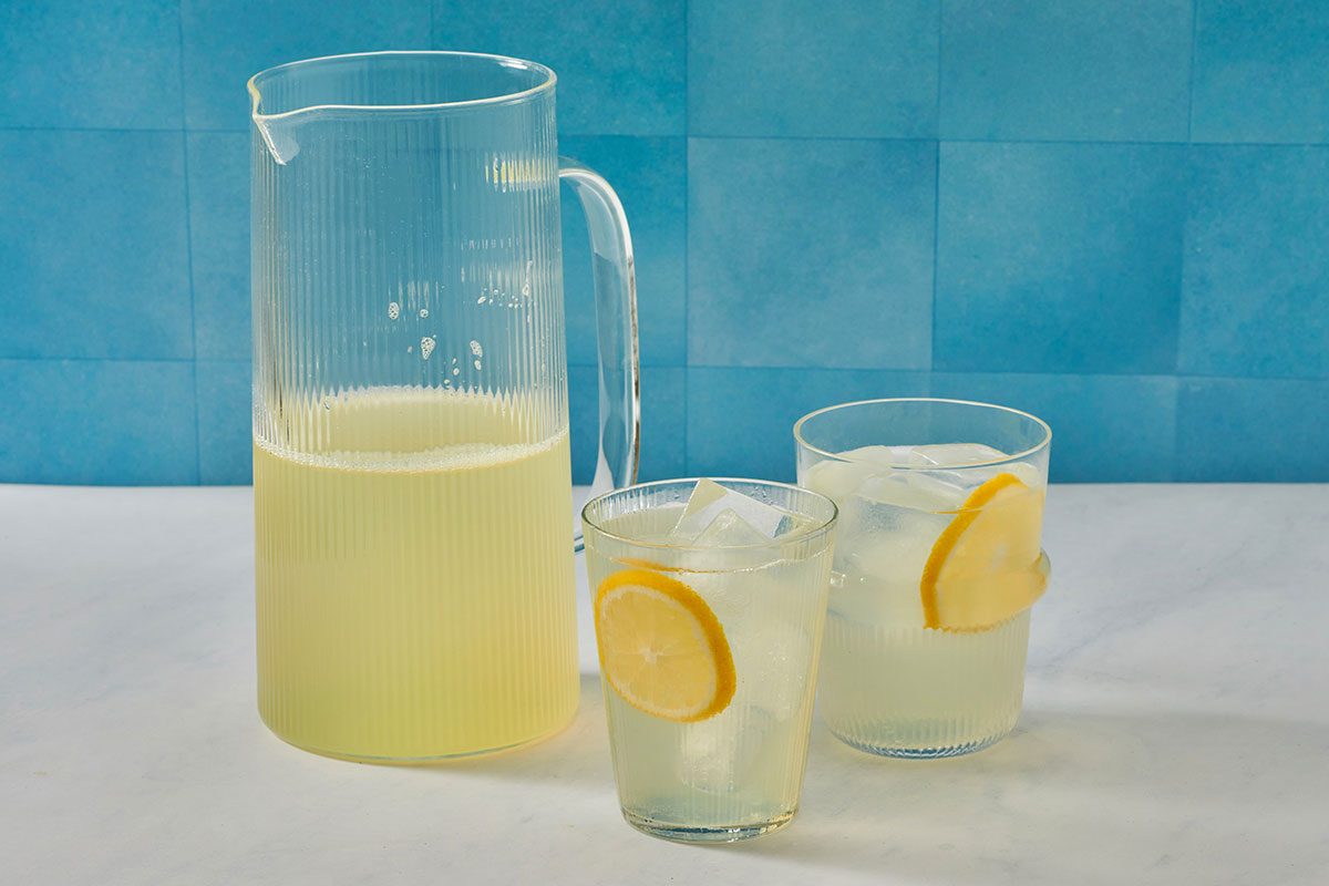 Lemonade in glasses filled with ice, with a pitcher nearby