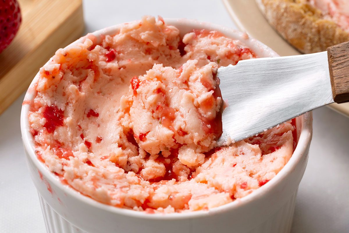 Strawberry Butter in a serving dish with a serving being taken out with a butter knife for Taste of Home