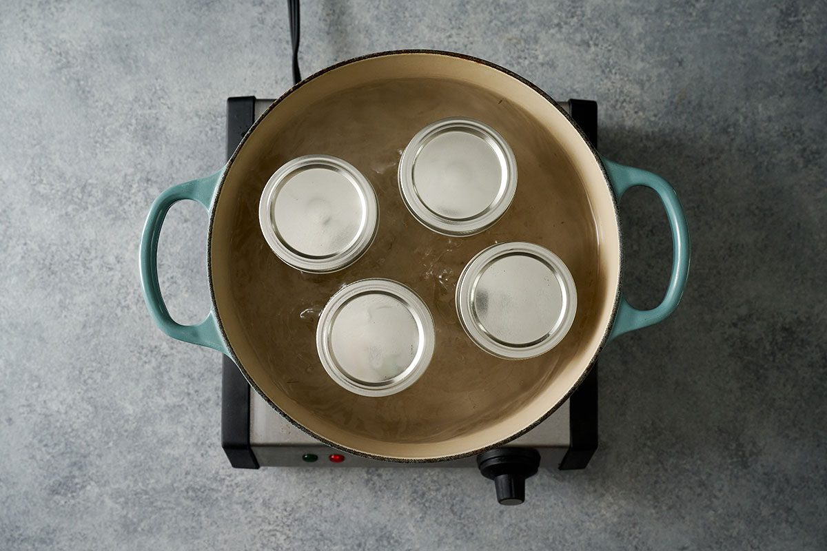 Overhead view of sealed jars of pickled sweet onions simmering in a canner, with water covering the jars for the Taste of Home Pickled Sweet Onions recipe.