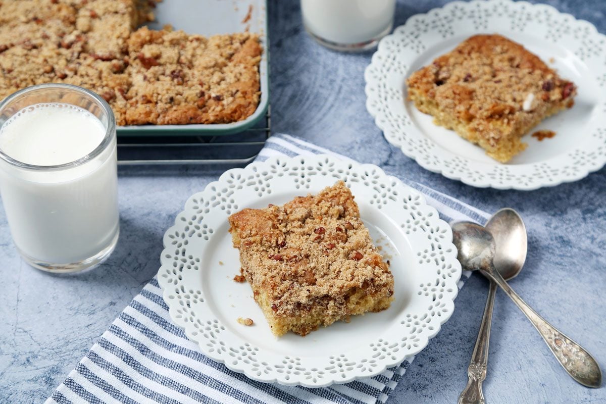 Close up of Taste of Home's Buttermilk Coffee Cake sliced and served on white plates on a light blue surface.