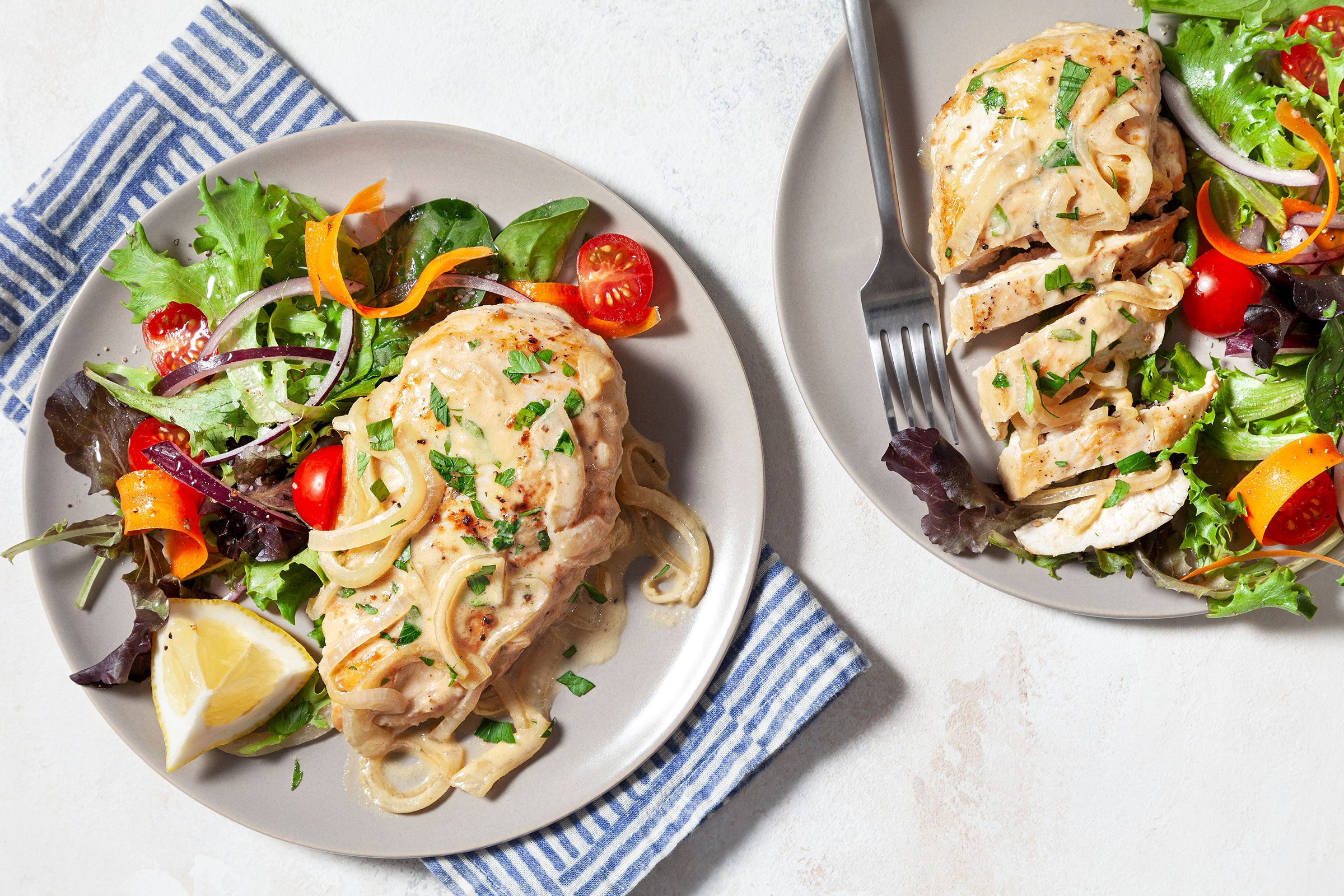 Chicken Dijon served on plates and sprinkled with some parsley with salad on side