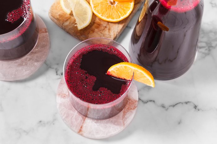 Beet juice served in a glass and placed on top of a coaster with lemon slice on the rim of the glass