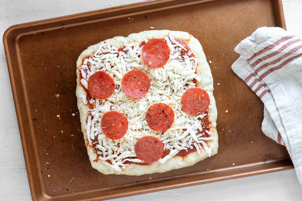 square shaped dough topped with cheese and pepperoni