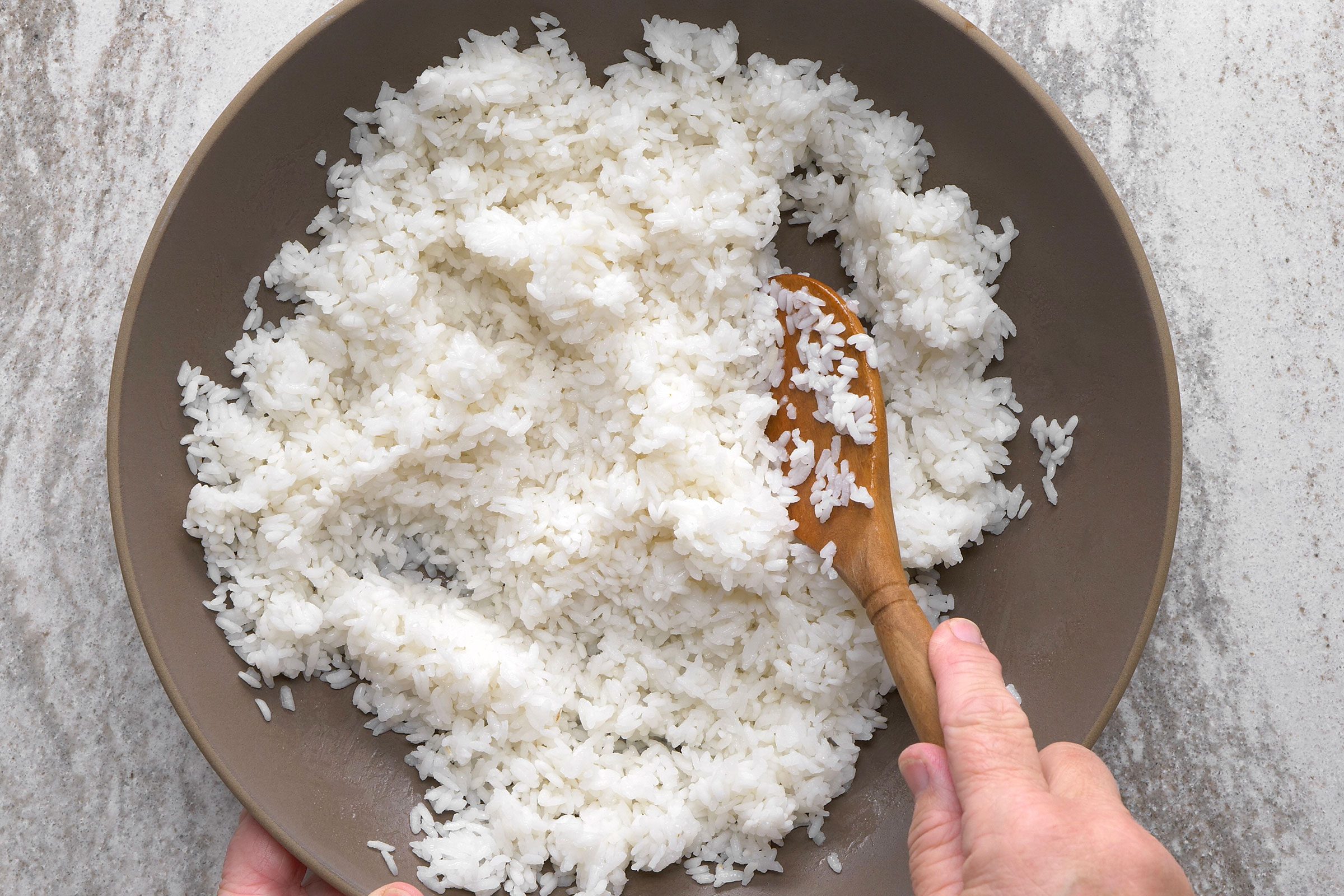 Sushi rice in a bowl with a wooden ladle in it