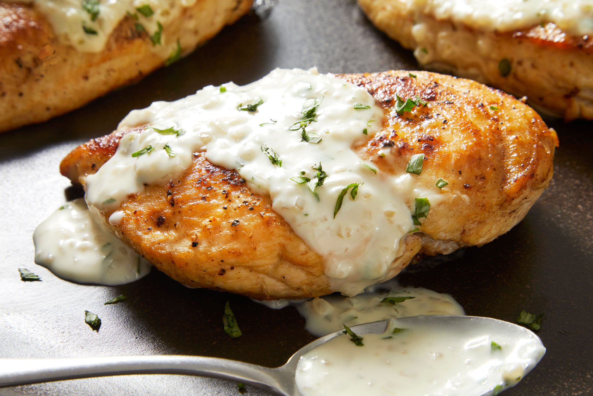 Close up shot of Chicken with Tarragon Sauce; Serve with chicken; Sprinkle with remaining tarragon; spoon; marble surface;
