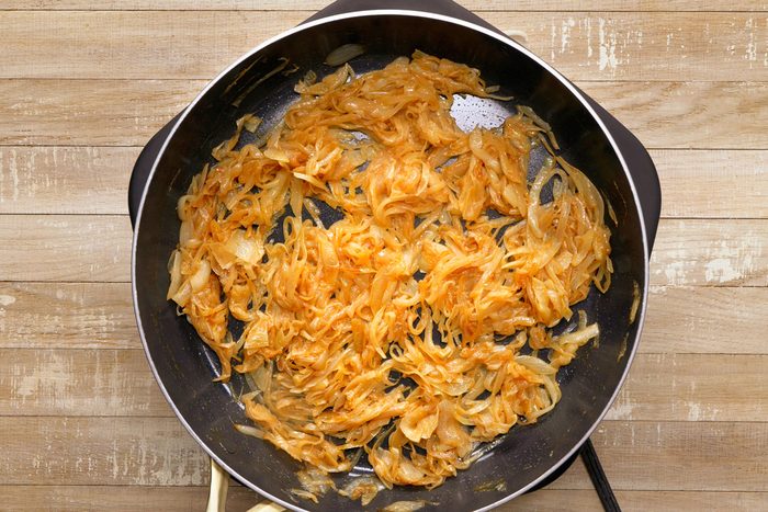 golden brown sliced onions being cooked in a skillet
