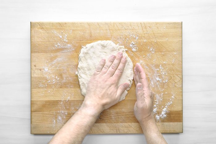Overhead shot of turn out onto a lightly floured wooden board; knead gently 8-10 times; wooden surface