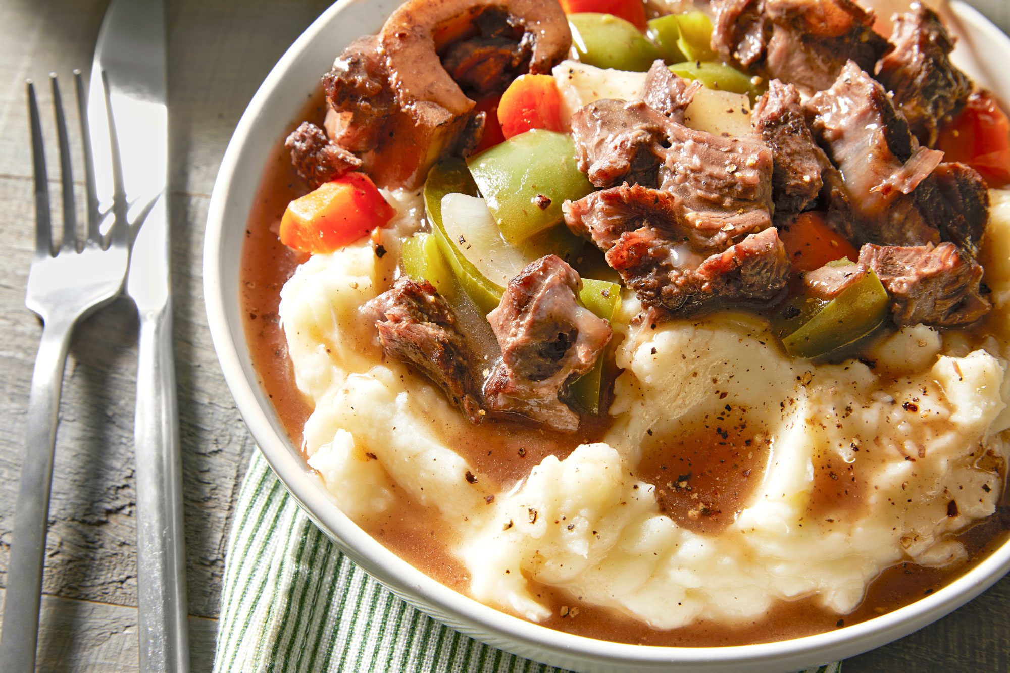 A bowl of creamy mashed potatoes topped with Instant pot beef shank and vegetables