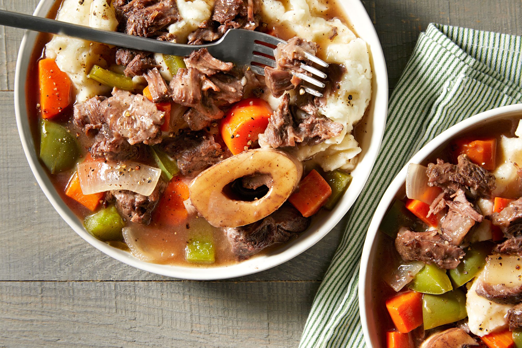 Bowls of creamy mashed potatoes topped with Instant pot beef shank and vegetables