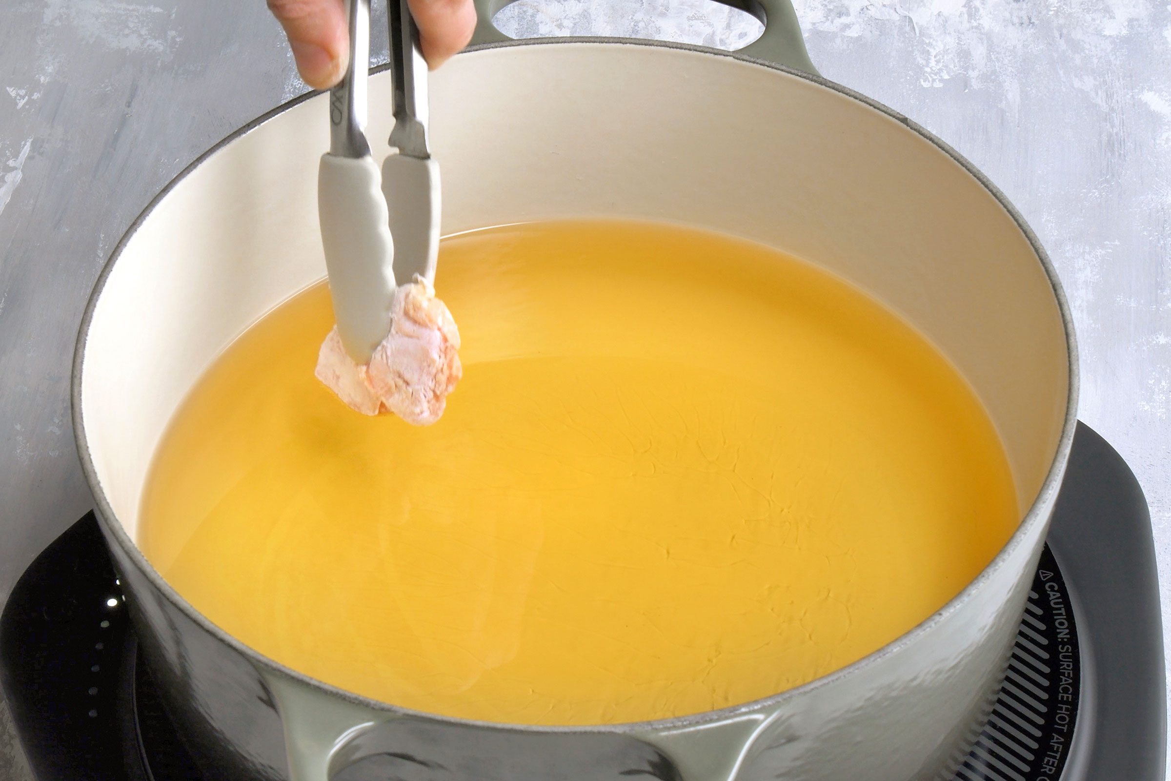 Marinated and cornstarch coated chicken piece put in oil for frying