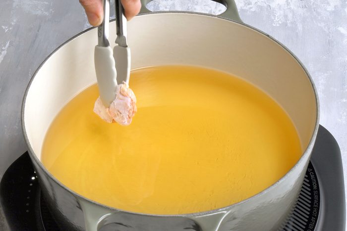 Marinated and cornstarch coated chicken piece put in oil for frying