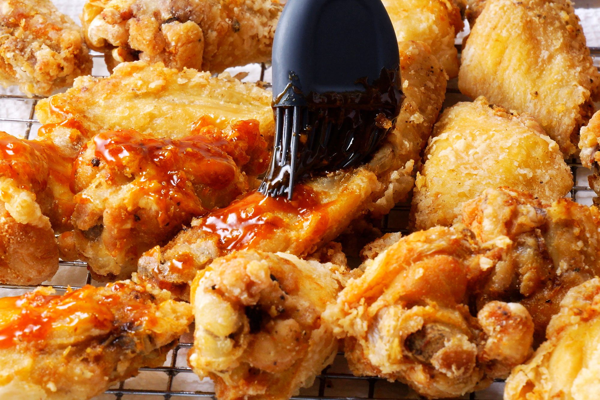 Applying the sweet and spicy sauce over the freid chicken wings