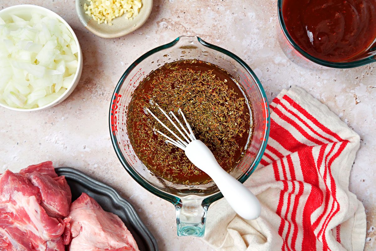 Liquid ingredients and spices mixed together in a large glass measuring cup.