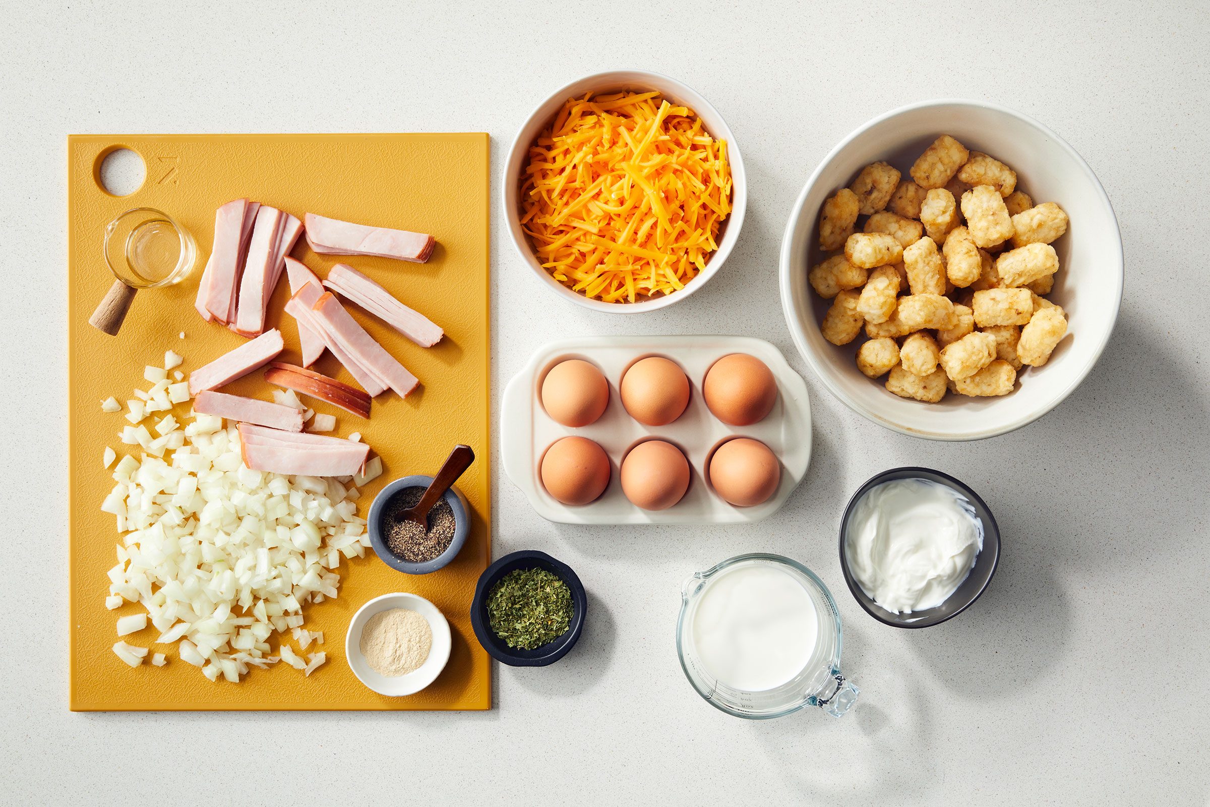 Ingredients for Tater Tot Breakfast Casserole in bowls and on wooden board