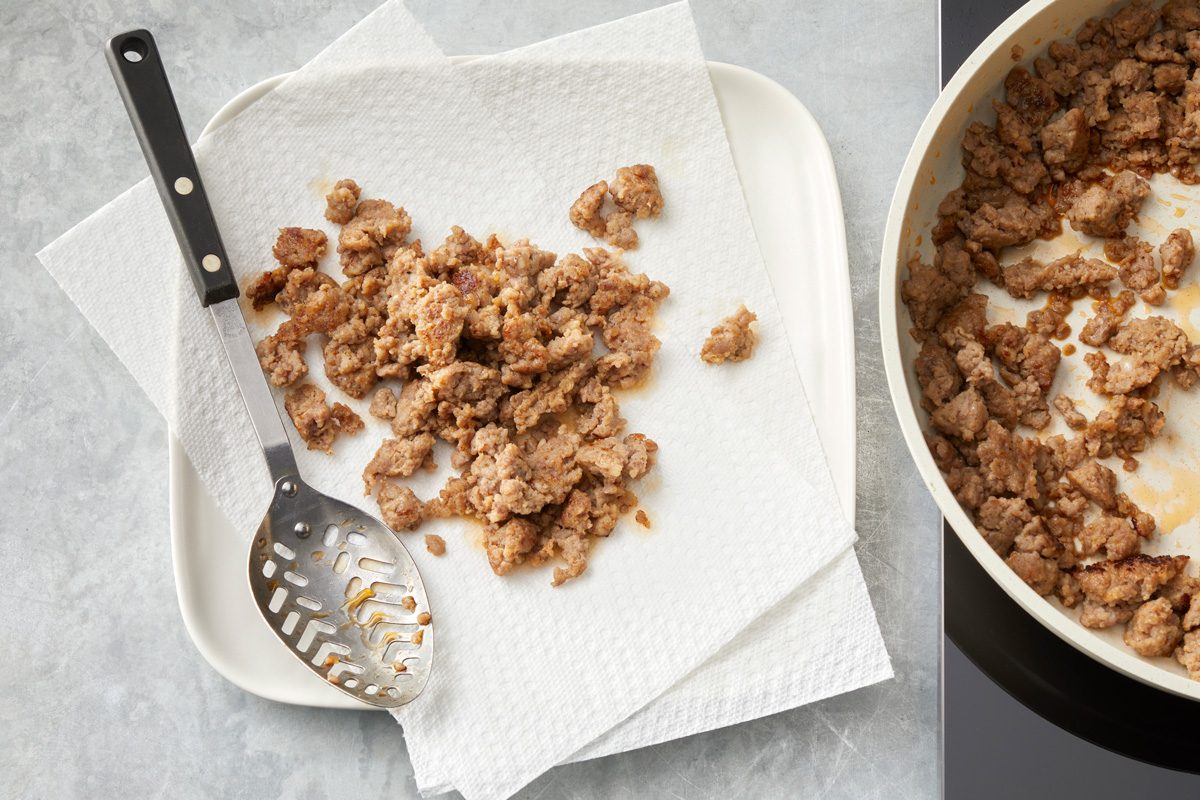 Overhead shot of remove with slotted spoon; drain on paper towels; Drain and discard fat; marble surface