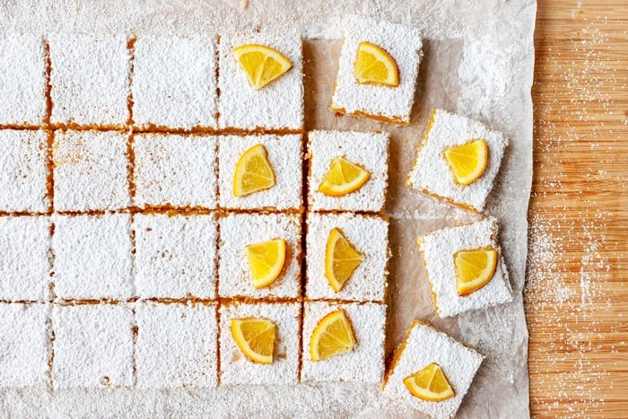 Meyer Lemon Bars being decorated and cut on a parchment paper covered surface
