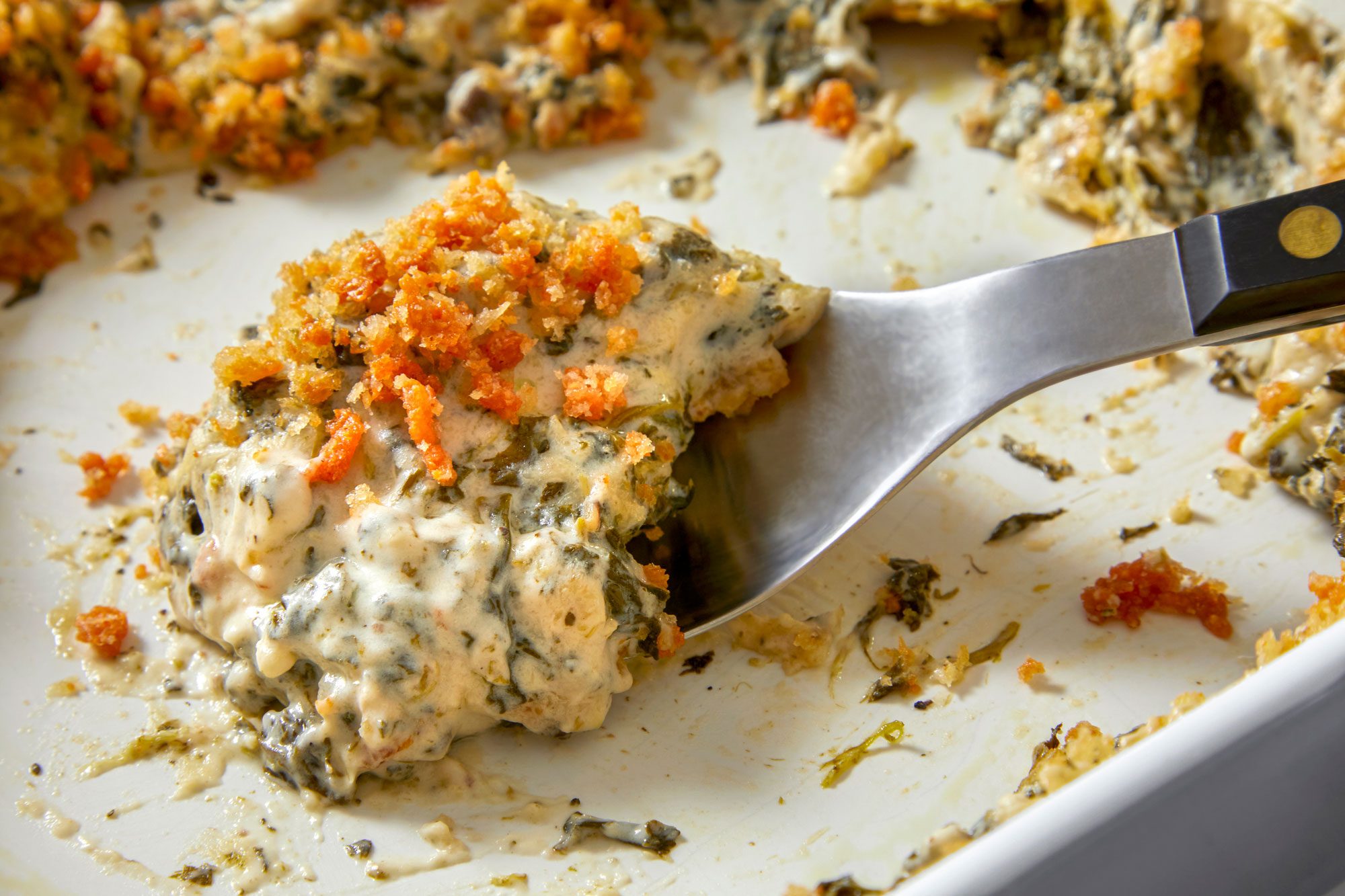 Close up shot of Easy Spinach Casserole in a baking pan with spoon