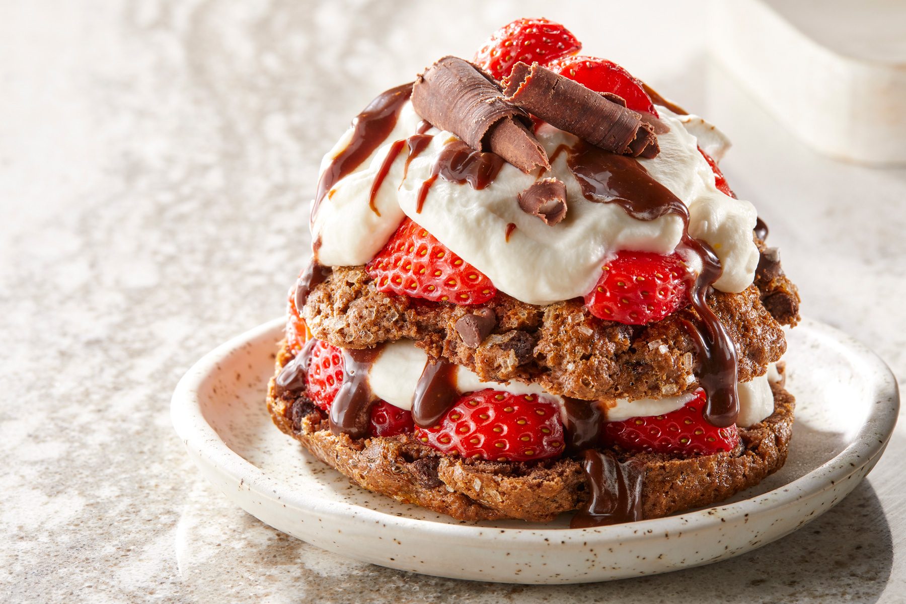 Table view shot of Chocolate Strawberry Shortcakes; garnished with chocolate; served on small plate; marble surface;