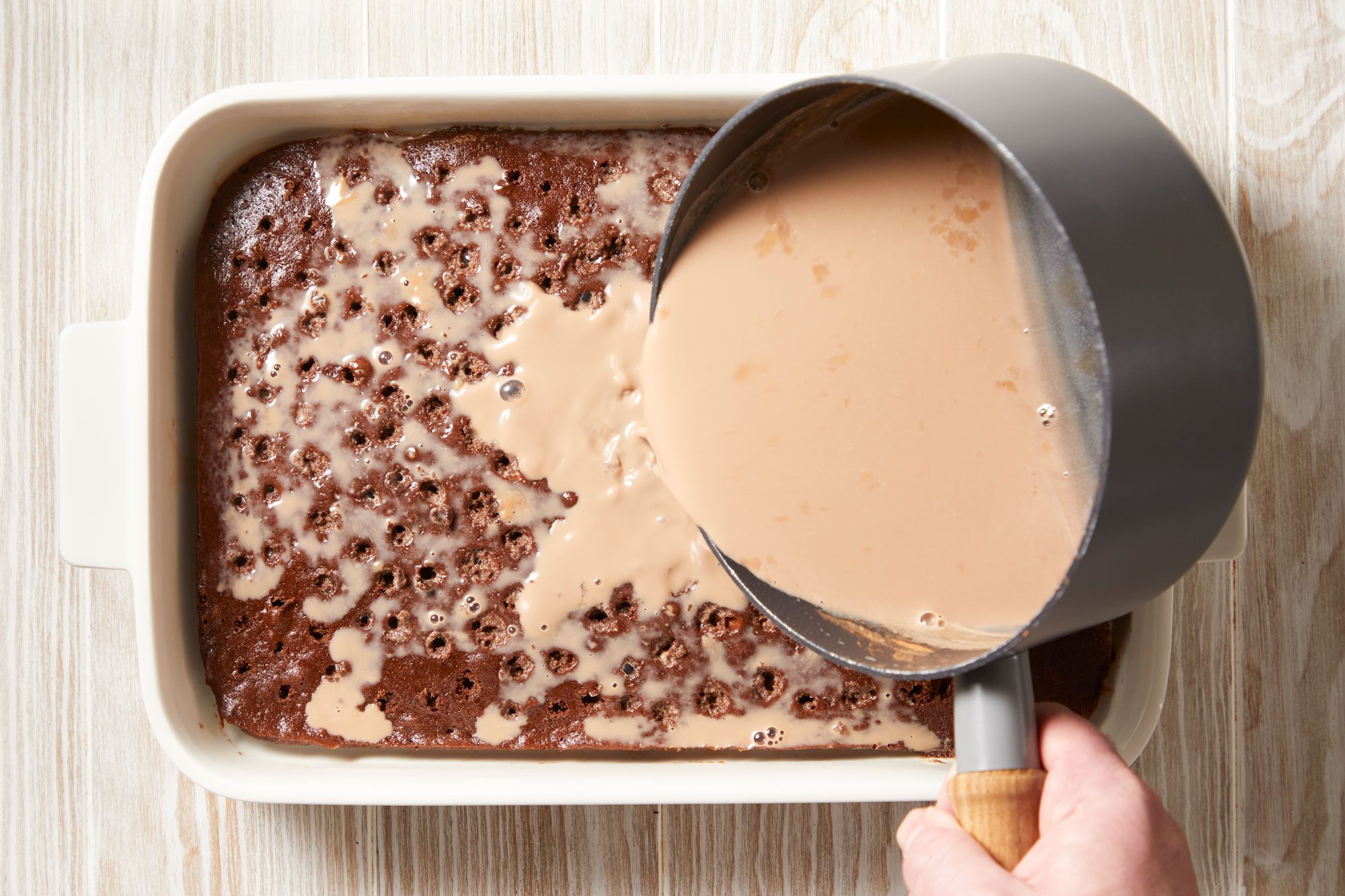 Slowly pour a third of the milk syrup over cake,