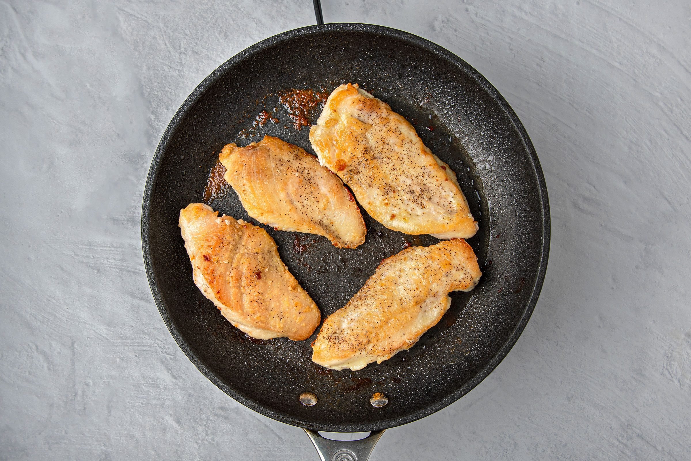 Chicken pieces cooking on a skillet until golden brown