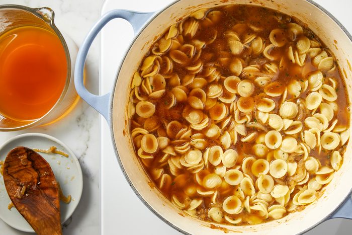 Salt, Worcestershire sauce, and black pepper added to the pan, followed by orecchiette pasta. Beef stock poured in to cover the pasta, with the rest set aside, and the heat raised to medium to bring the liquid to a simmer while stirring frequently to prevent sticking.