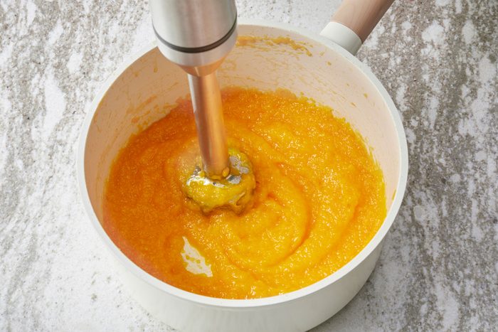 Using an immersion blender to puree the mango mixture