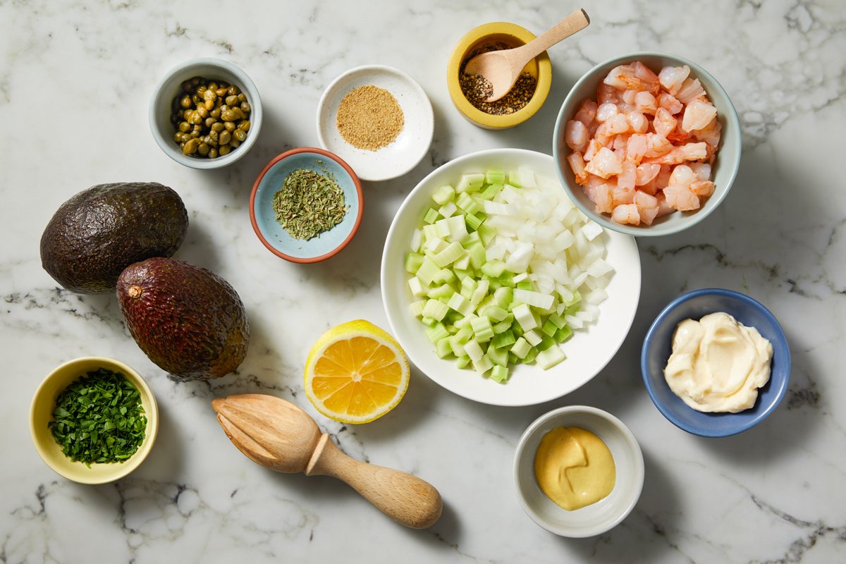 Overhead shot of all ingredients for Shrimp Salad Stuffed Avocados; all set on marble surface;