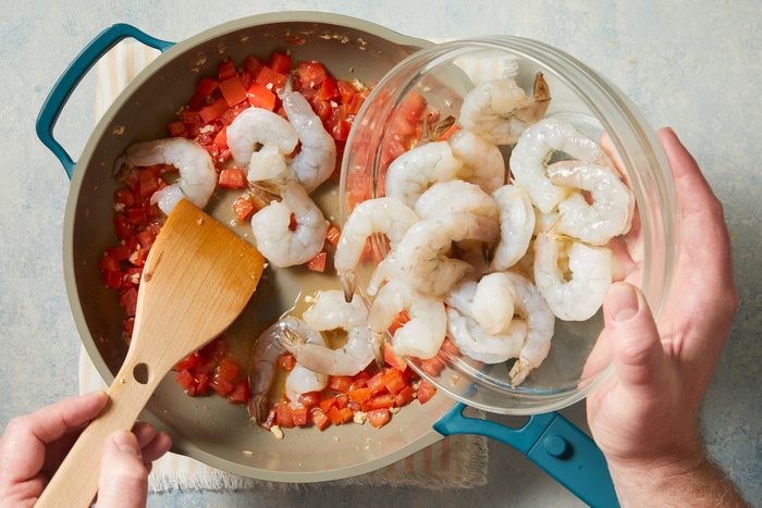 shrimp being added to skillet for cooking