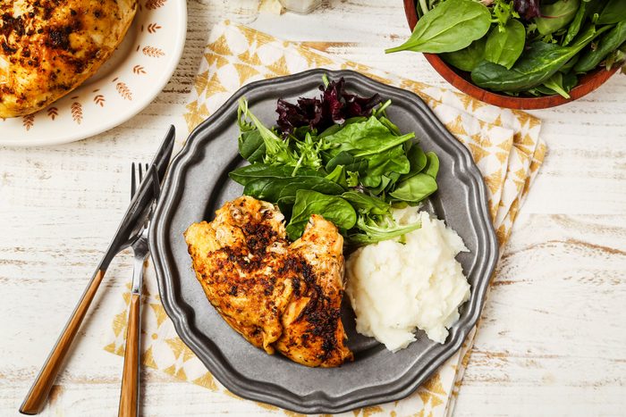 Cover push pull image of Taste of Home's Slow-Cooker Bone-In Chicken Breast shot on a white wooden surface; Bone-in chicken breasts cookedi n a slow-cooker and served on a metal plate with mashed potatoes and greens