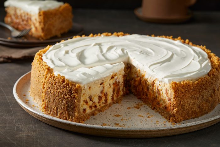 table view shot of Snickerdoodle Cheesecake; placed on a large plate; cut a slice and served on a small plate with a fork; and a coffee mug; all set on a dark surface;