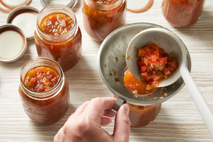 relish being ladled into sterilised pint jars
