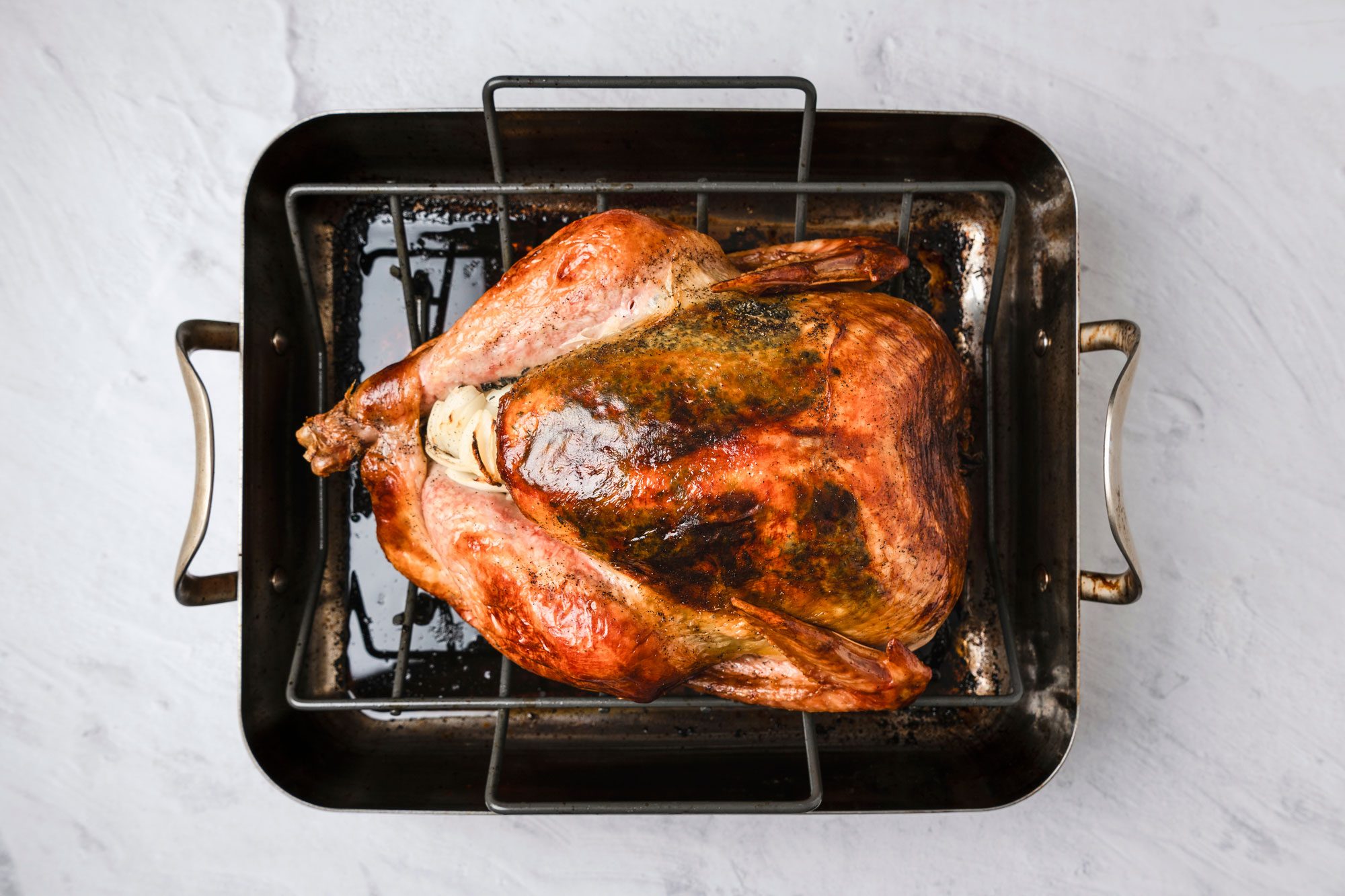 Overhead shot; Remove and discard cheesecloth; Bake turkey until a thermometer inserted in the thigh reads 170-175 degree basting occasionally with pan drippings; 45 minutes to 1-1/4 hours longer; Remove turkey to a serving platter; cover and let stand 20 minutes before carving; Discard vegetables from cavity; marble surface;