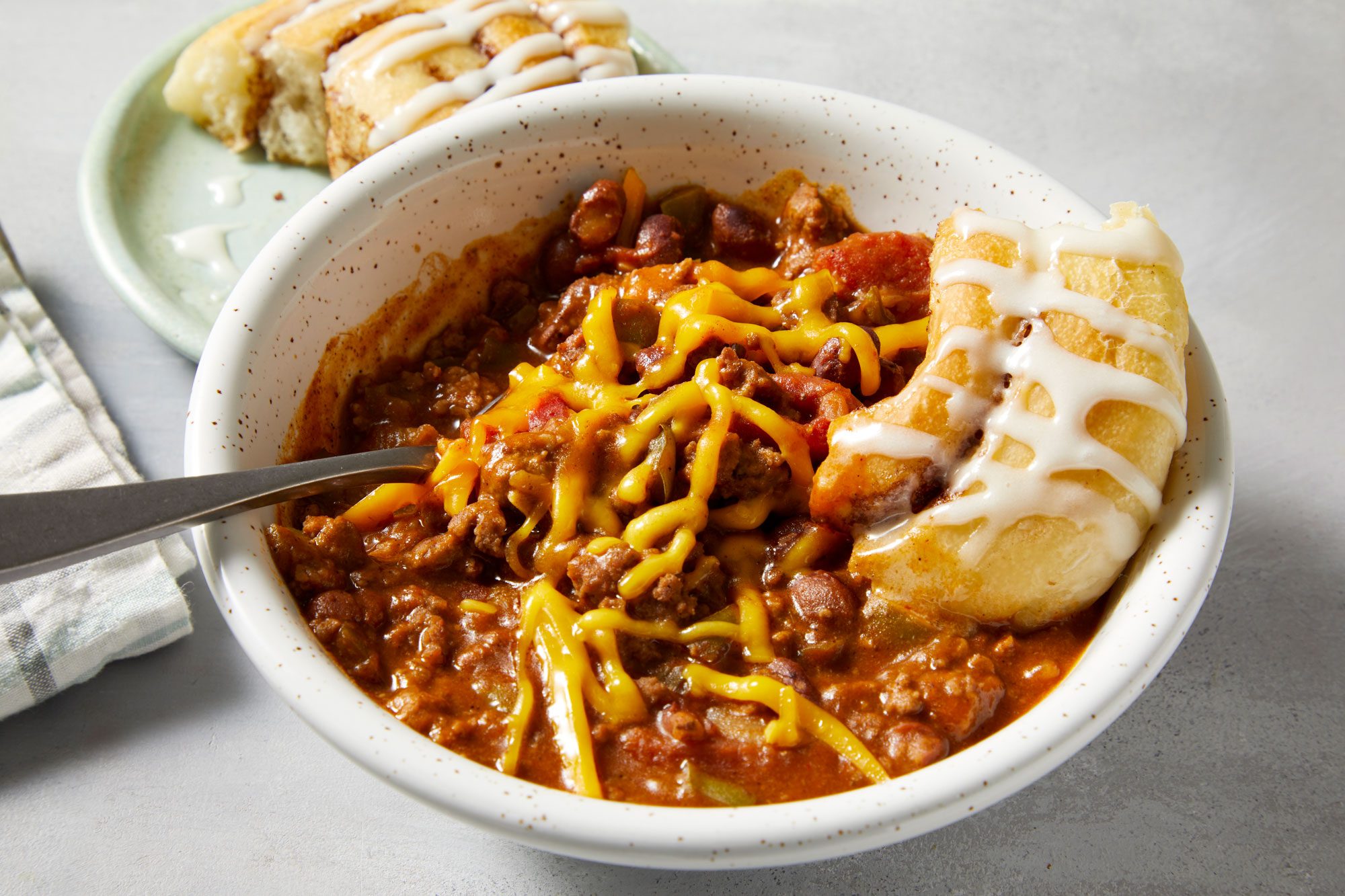 Chili And Cinnamon Rolls served in a ceramic bowl with spoon