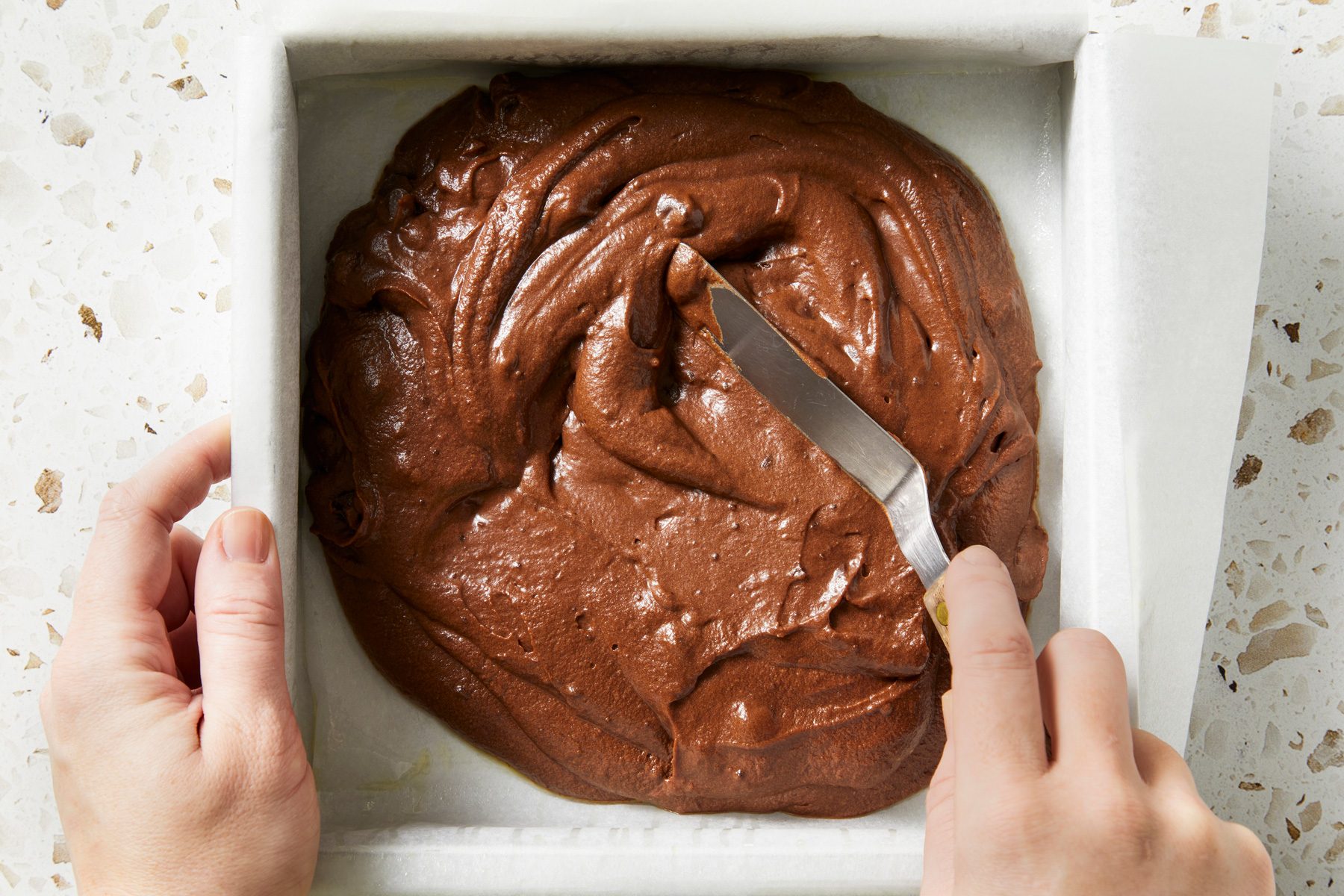Close up shot of spread batter into the prepared baking pan; Bake 40-45 minutes or until a toothpick inserted in the center comes out clean; knife; marble surface;