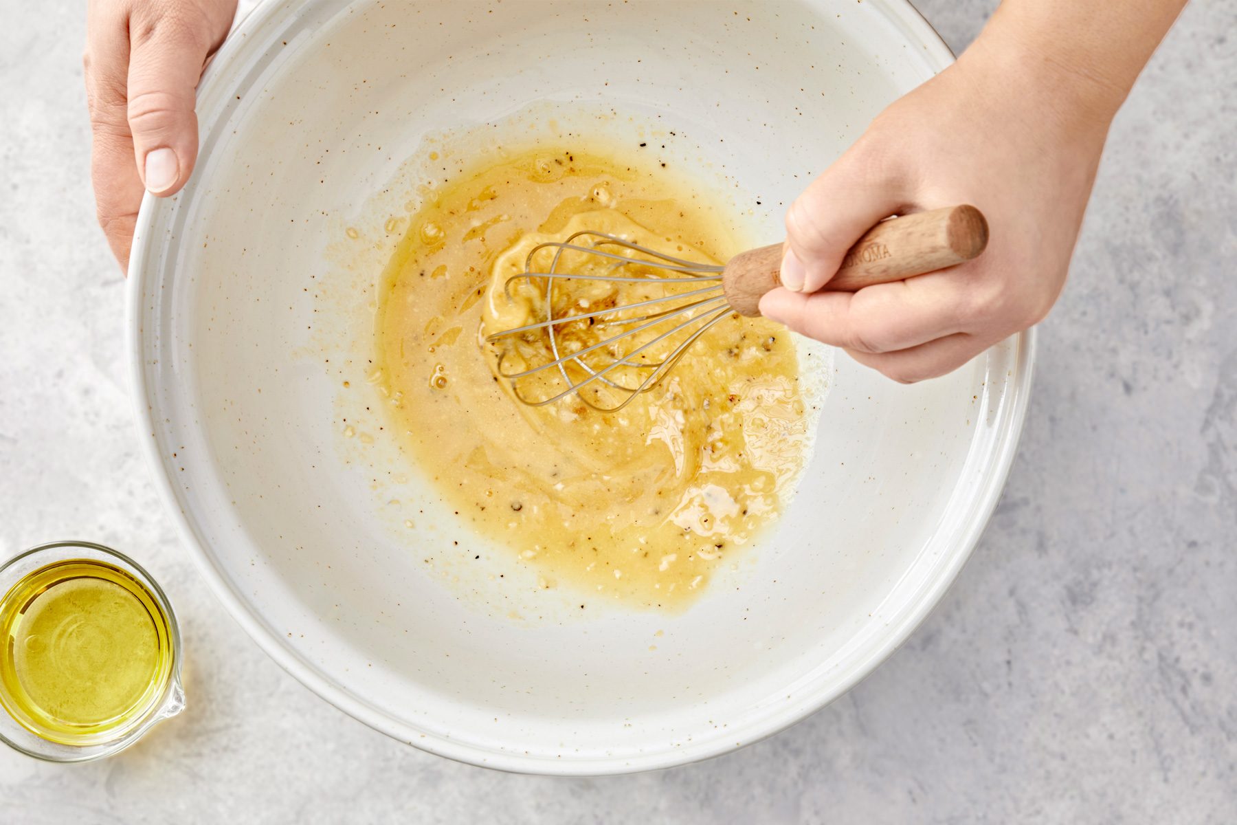 overhead shot of a large bowl, whisking together vinegar, mustard, honey, garlic, salt, pepper and onion powder