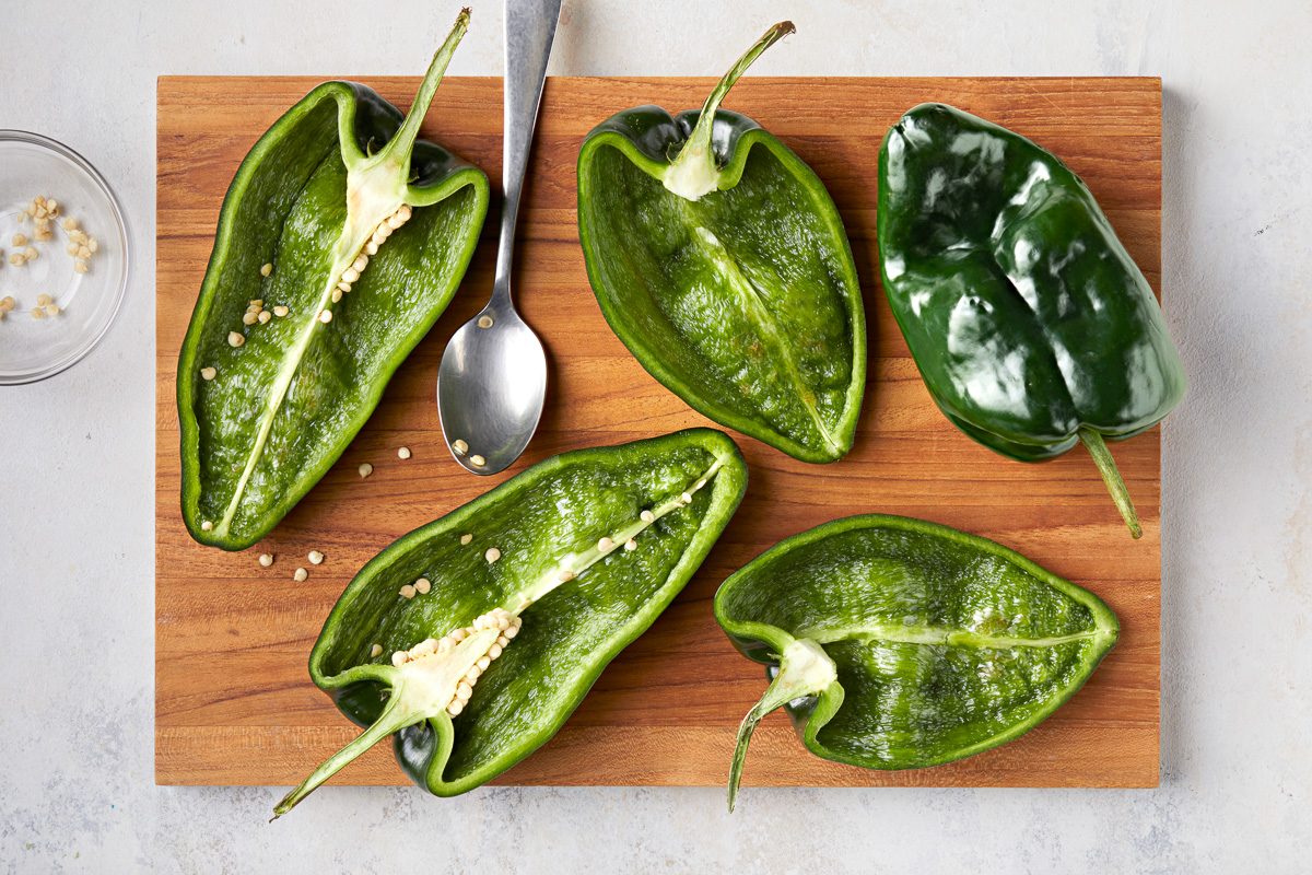 poblano peppers cut in half on a chopping board