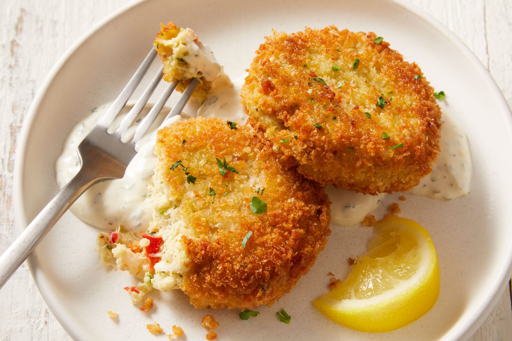 closeup shot of a plate of Company Shrimp and Crab Cakes arranged neatly, and accompanied by fresh lemon wedge;