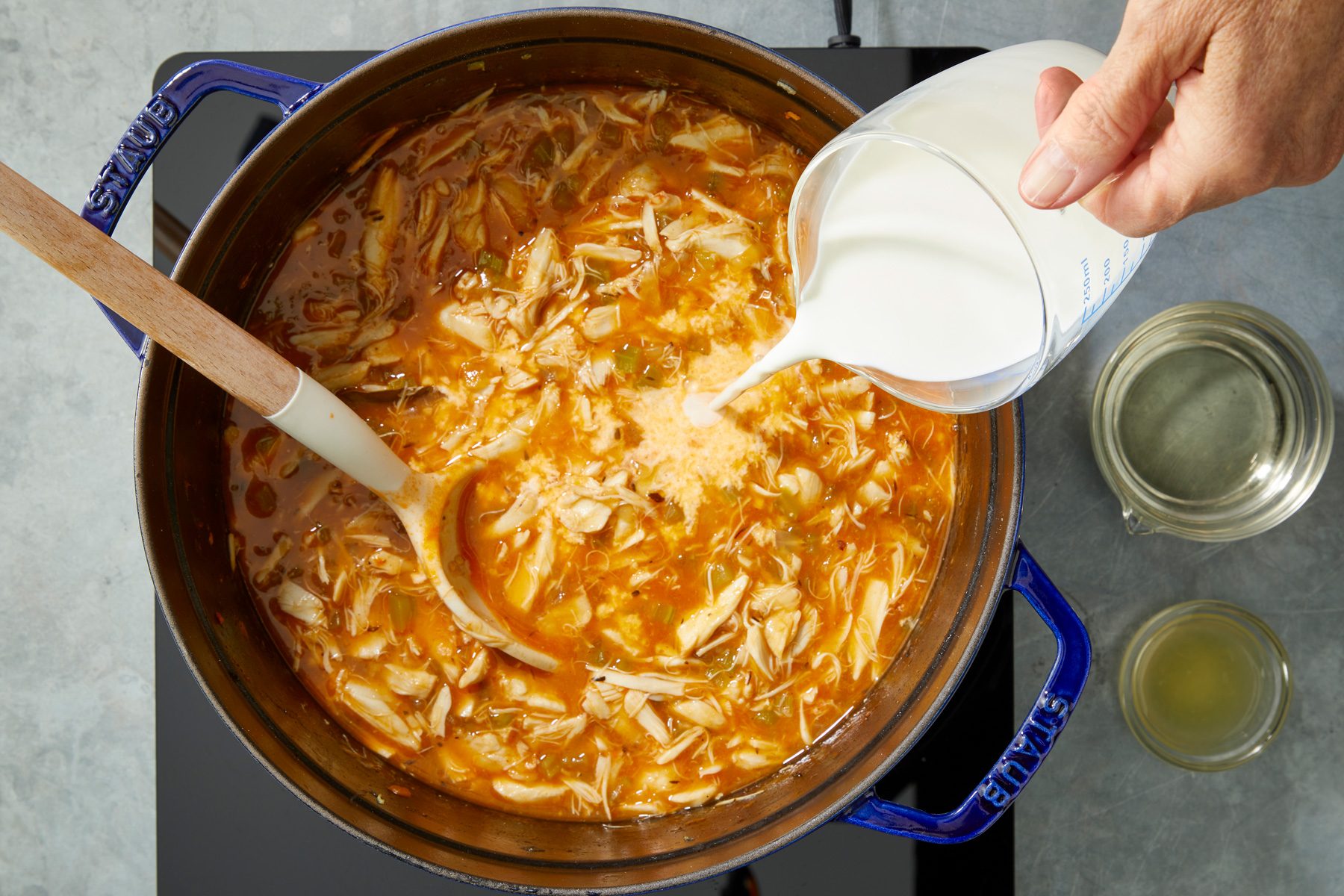 Overhead shot of stir in cream; wine; and lemon juice; heat through; Discard bay leaves; spoon; induction; grey surface;
