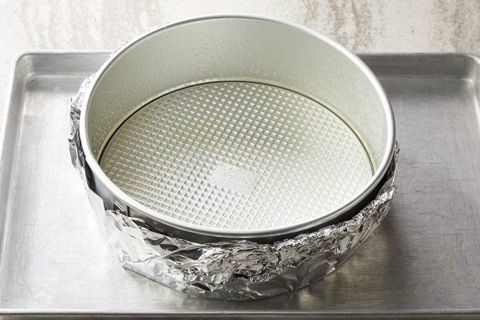 Place a greased 9 inch springform pan on a double thickness of heavy duty foil about 18 inch square; Wrap foil securely around pan; Place on a baking sheet
