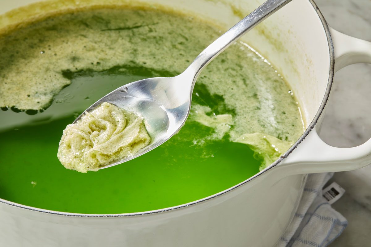 Close-up shot of skim off foam; Ladle hot liquid into hot half-pint jars; leaving 1/4-inch headspace; napkin; marble surface;